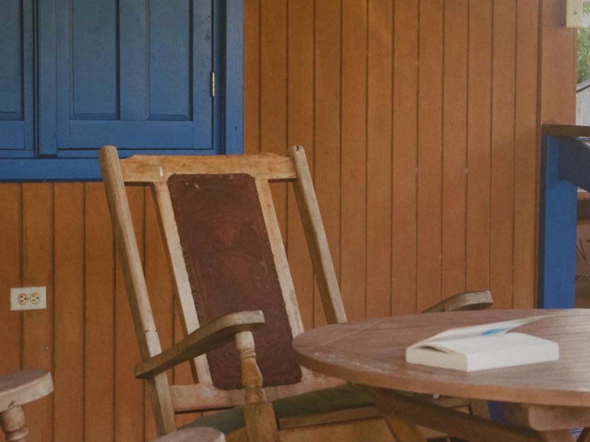 Mecedora de madera y mesa con un libro abierto en un balcón